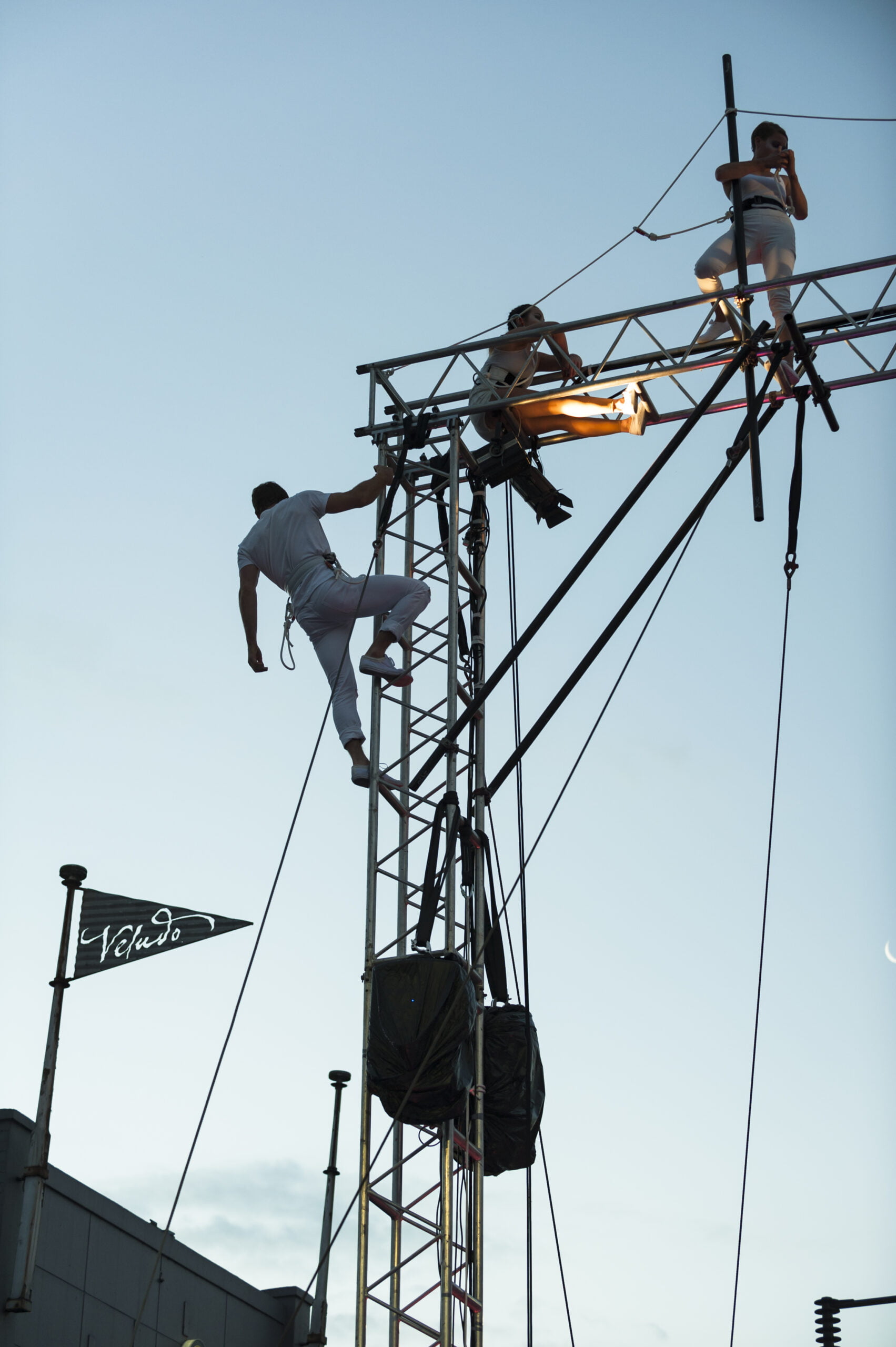 Three Circus artists climb a structure made from scaffolding
